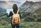 Hipster young girl with bright backpack enjoying sunset on peak of foggy mountain, looking a map and poining hand. Tourist travele