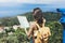 Hipster young girl with bright backpack looking at a map and poining hand the travel plan. View from the back of the tourist trave