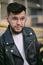 Hipster young man with a beard portrait urban leather coat close up sunny day