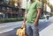 Hipster young man holding in hands backpack with map. Front view tourist traveler planning route and standing at the road on back
