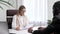 Hiring, interview. Middle-aged blond business woman conducting an interview in a bright office, an African American man