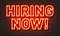 Hiring now neon sign on brick wall background.