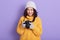 Hirizontal shot of beautiful young girl wearing cap, knitted sweater holding camera and looking at digital photos, spending winter