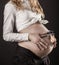 His First Portrait... Happy Pregnant Woman holding funny glasses on to her belly, close up, on black background