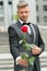 His look very fashion-forward. groom in costume and bow-tie. man give you rose. reason to give red rose. where to wear