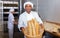 Hispanic baker showing fresh baked baguettes in bakery