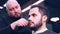 hispanic bearded man having his hair cut by hairdresser at the barbershop