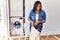 Hispanic brunette woman hanging clean laundry on rack at laundry room