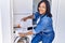 Hispanic brunette woman putting detergent into mashing machine at laundry room