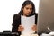 Hispanic Businesswoman Organizing Paperwork While Talking On Phone