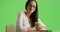 A Hispanic businesswoman poses for a portrait holding a coffee on green screen