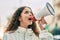 Hispanic child girl shouting angry using megaphone at the city