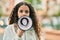 Hispanic child girl shouting angry using megaphone at the city