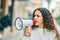 Hispanic child girl shouting angry using megaphone at the city