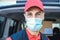 Hispanic delivery man smiling on camera while wearing safety mask - Focus on face