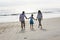 Hispanic family holding hands walking on beach