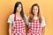 Hispanic family of mother and daughter wearing baker uniform over yellow background thinking attitude and sober expression looking