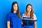 Hispanic family of mother and daughter wearing casual clothes over blue background depressed and worry for distress, crying angry