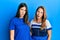 Hispanic family of mother and daughter wearing casual clothes over blue background in shock face, looking skeptical and sarcastic,