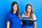 Hispanic family of mother and daughter wearing casual clothes over blue background skeptic and nervous, frowning upset because of