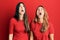 Hispanic family of mother and daughter wearing casual clothes over red background angry and mad screaming frustrated and furious,