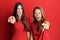 Hispanic family of mother and daughter wearing casual clothes over red background pointing displeased and frustrated to the