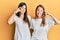 Hispanic family of mother and daughter wearing casual white tshirt smiling pointing to head with one finger, great idea or