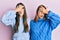 Hispanic family of mother and daughter wearing wool winter sweater peeking in shock covering face and eyes with hand, looking