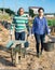 Hispanic farmer couple carrying wheelbarrow and bucket