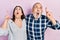 Hispanic father and daughter wearing casual clothes amazed and surprised looking up and pointing with fingers and raised arms