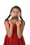 Hispanic female child in red dress eating chocolate donut with hands and mouth stained and dirty smiling happy