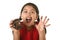 Hispanic female child in red dress eating chocolate donut with hands and mouth stained and dirty smiling happy