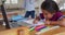 Hispanic girl sitting at table drawing with mother in background