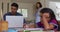 Hispanic girl sitting at table drawing with parents working in background