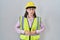 Hispanic girl wearing builder uniform and hardhat with hand on stomach because indigestion, painful illness feeling unwell