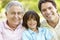 Hispanic Grandfather, Father And Son Relaxing In Park