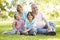 Hispanic Grandmother And Grandfather Relaxing With Grandchildren In Park