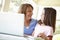 Hispanic Grandmother Using Laptop And Calculator With Granddaughter