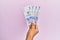 Hispanic hand holding 50 colombian pesos  banknotes over isolated pink background