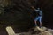 A Hispanic hiker raising his arms while standing on rocks in the Gruta de Totomachapa cave, Mexico