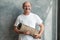 Hispanic male pensioner looking at camera while holding yoga mat in hands