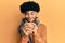 Hispanic man with afro hair smelling coffee aroma relaxed with eyes closed