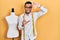 Hispanic man with beard dressmaker designer standing by manikin smiling making frame with hands and fingers with happy face