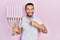 Hispanic man with beard holding menorah hanukkah jewish candle smiling happy pointing with hand and finger