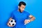 Hispanic man with beard holding soccer ball looking at the watch time worried, afraid of getting late