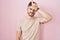 Hispanic man with beard standing over pink background making fun of people with fingers on forehead doing loser gesture mocking