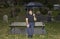 Hispanic man sitting on bench with lowered head in cemetery