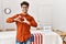 Hispanic man standing by election room smiling in love doing heart symbol shape with hands