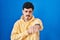 Hispanic man standing over blue background punching fist to fight, aggressive and angry attack, threat and violence