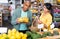 Hispanic married couple choosing bananas in grocery store